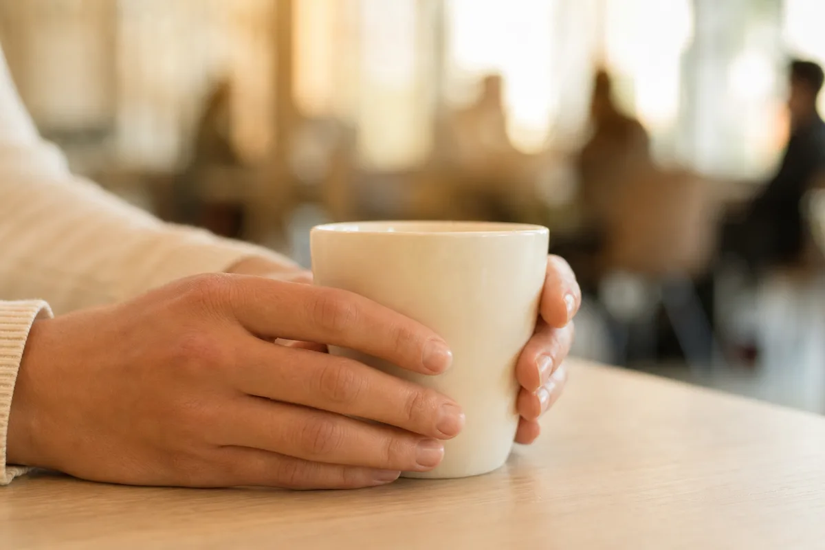 Mains tenant une tasse de café dans un espace de coworking
